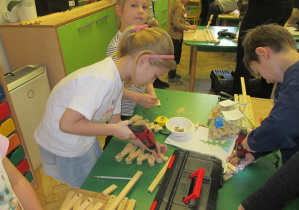 Dziewczynka wykonuje choinkę z elementów drewnianych