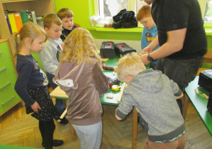 Dzieci otrzymują profesjonalne instrukcje wykonania drewnianych choinek