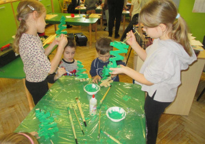 Dziewczynki z chłopcem malują złożone choinki